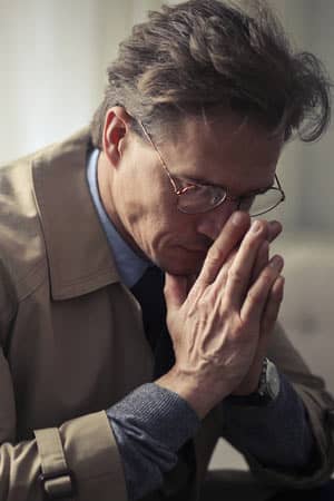  Man sitting with hands to his face.