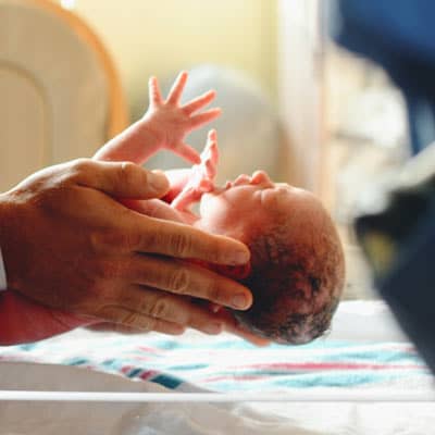  Newborn held by someone.